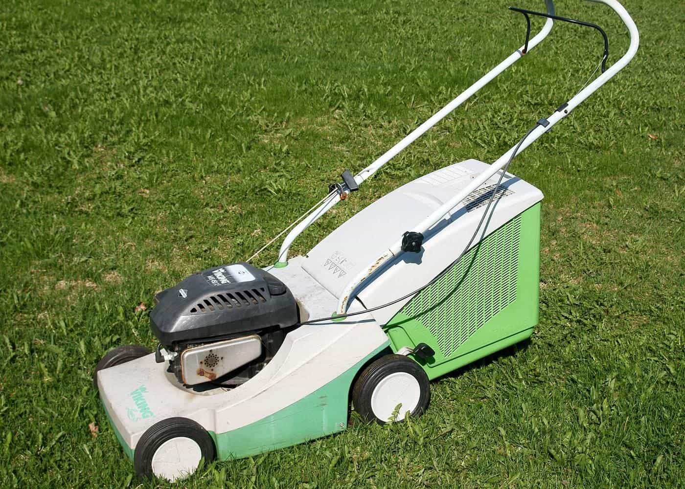 A white and green battery lawn mower standing on a lawn