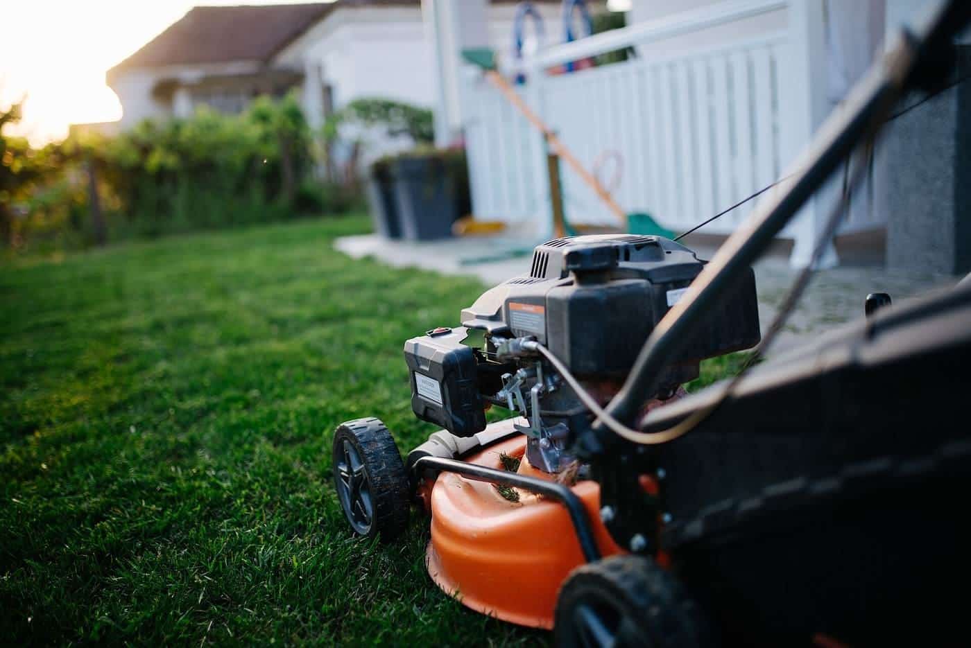 An orange and black walk-behind lawn mower sitting on a freshly cut lawn